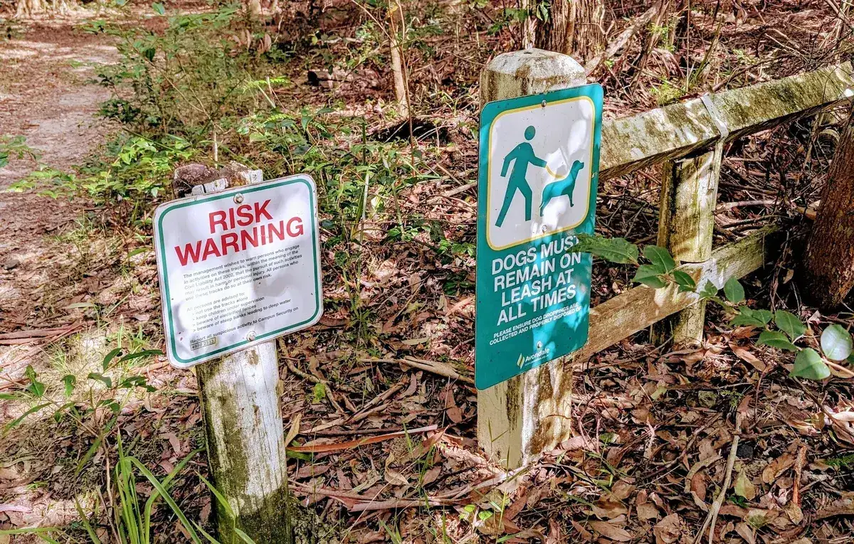 Risk warning and dogs on leash signs at the track entrance