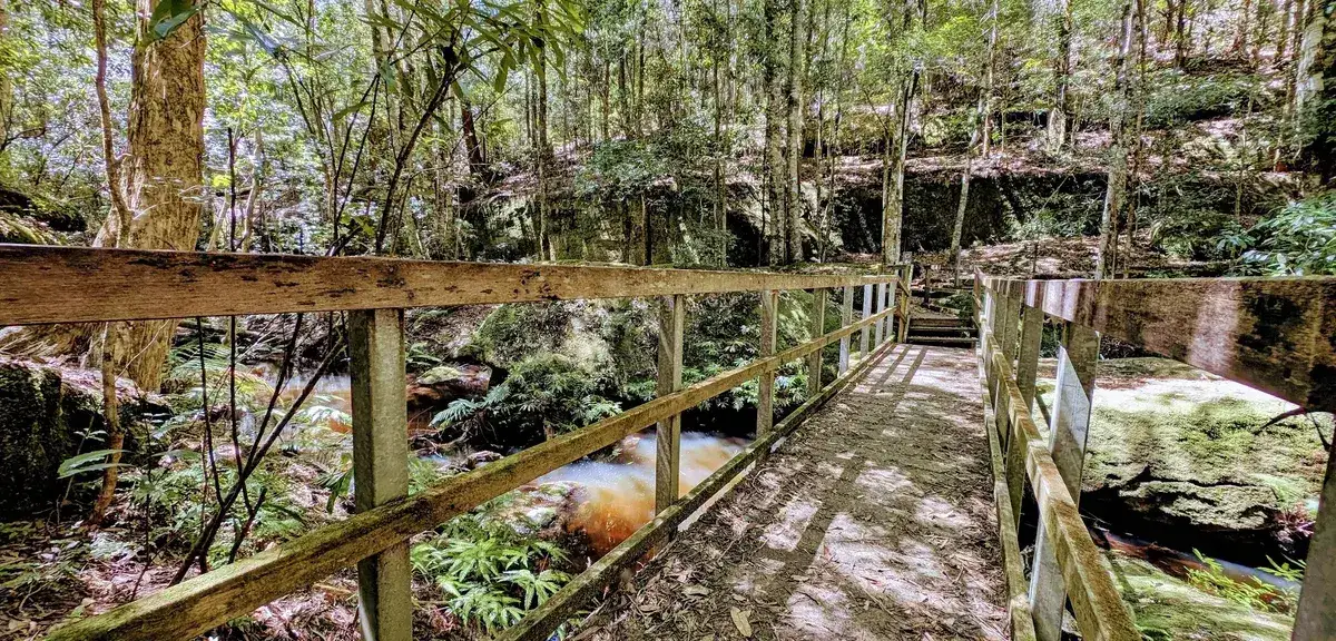 Timber bridge crossing the creek beneath a sandstone bluff