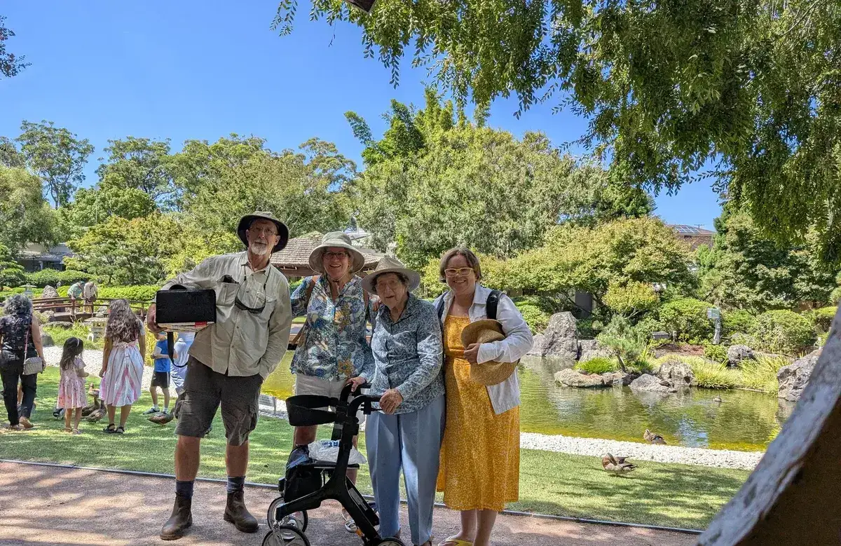 Group of four adults standing beside a pond in the Japanese gardens