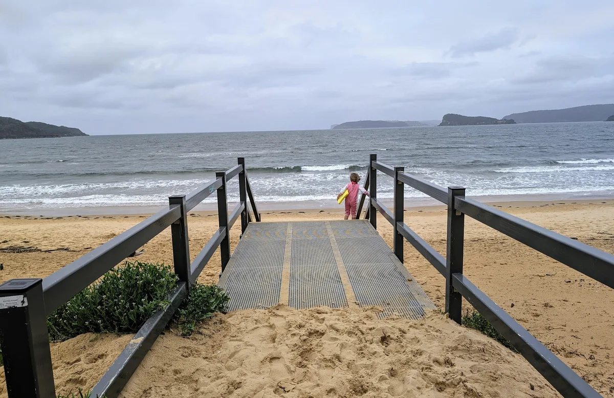 Child walking down a beach access ramp toward the water