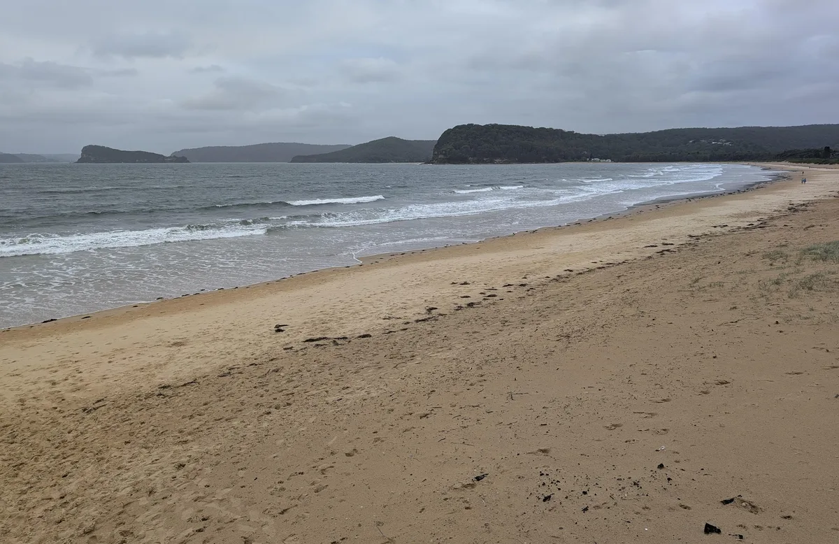 Empty beach with footprints leading toward a distant headland