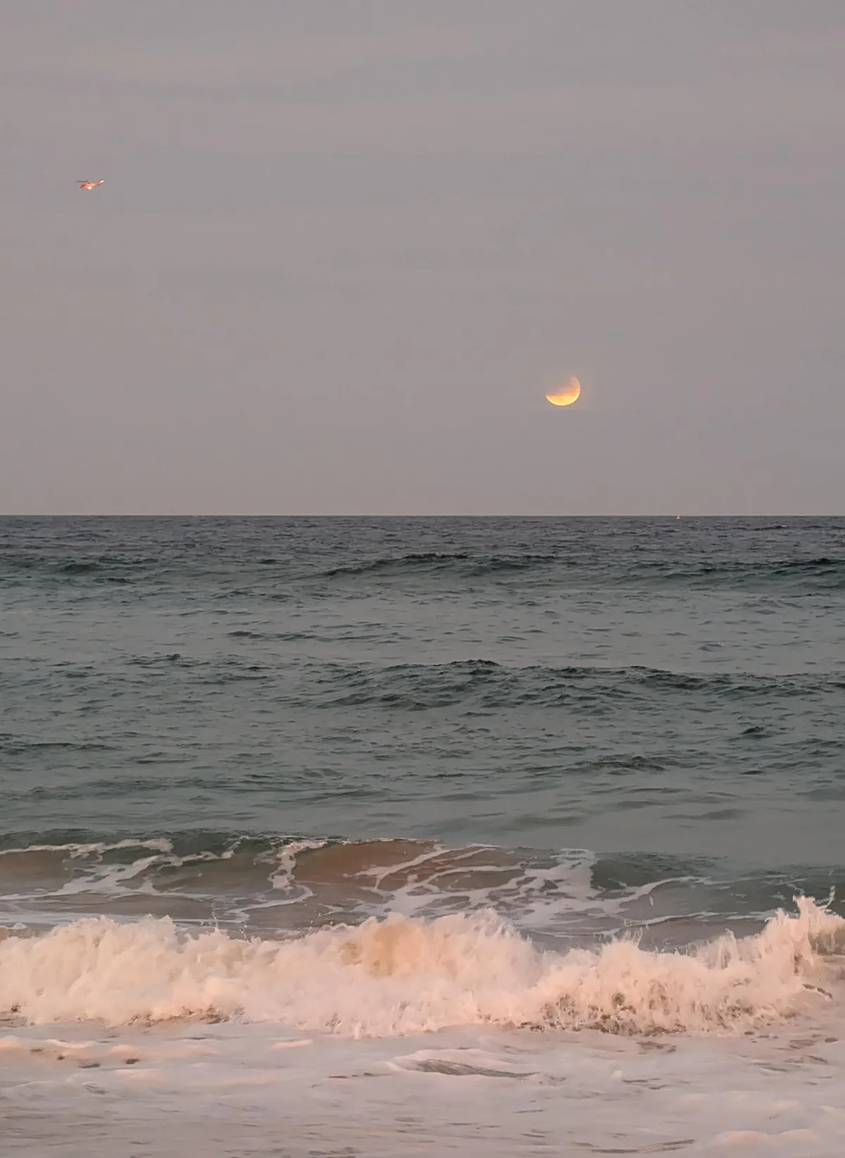 Crescent moon rising over breaking waves at North Avoca beach