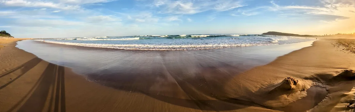 Panoramic Toowoon Bay cove with long shadows stretching across the sand