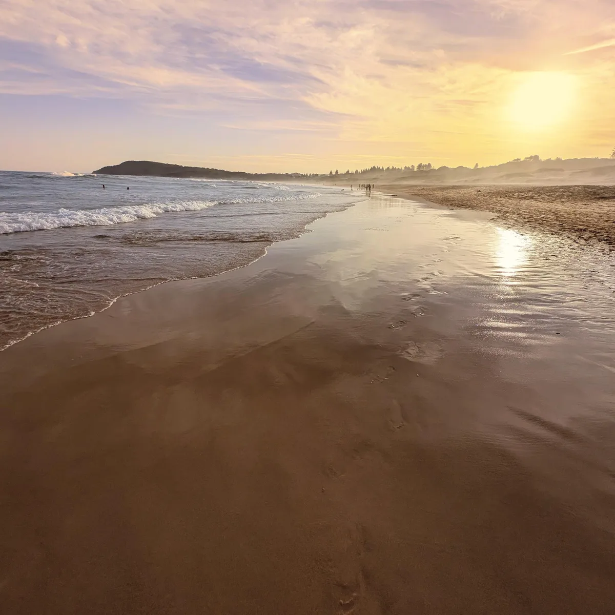 Golden sunset light reflecting on wet sand along the shoreline