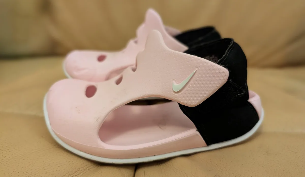 Pink and black toddler Nike sandals side by side