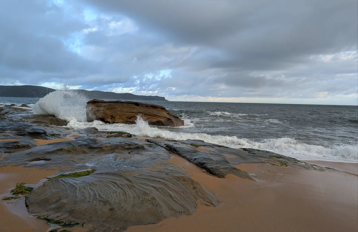 Wave crashing over a rock platform at the Pearl Beach headland